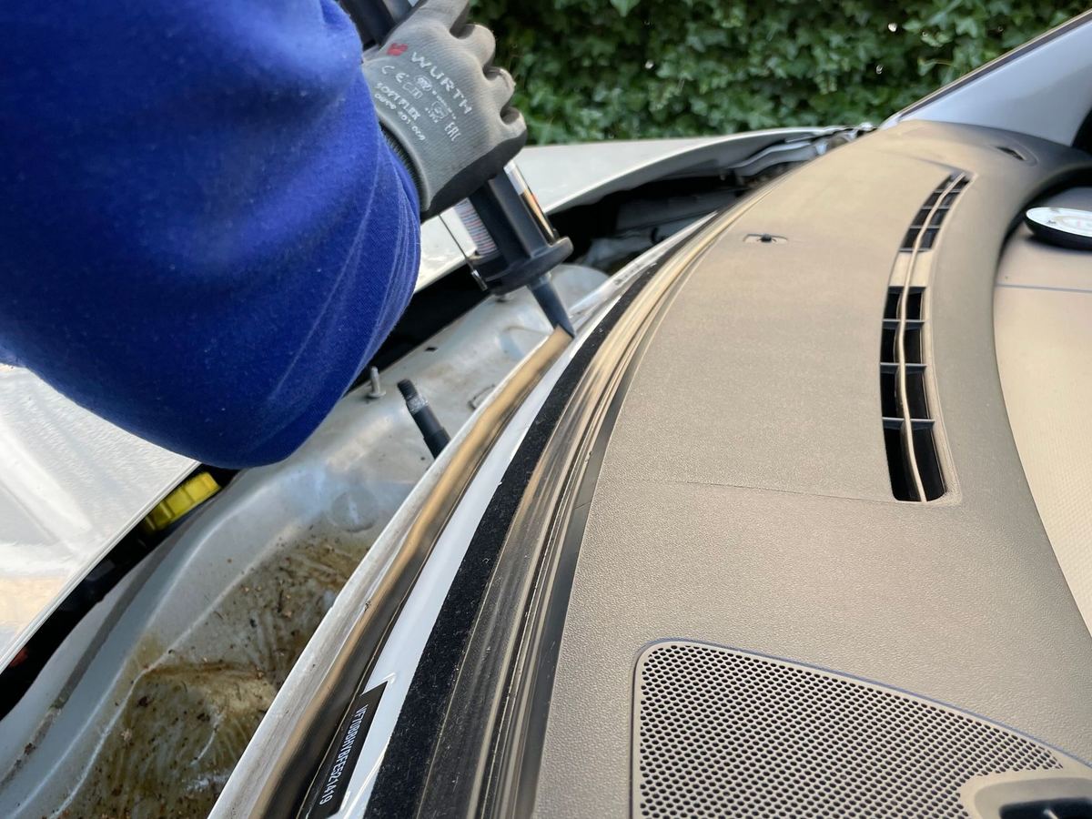 Technician working on a vehicle with the windscreen removed